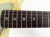 Close-up of vintage electric guitar rosewood fretboard with metal frets and dot inlays on cream-colored body