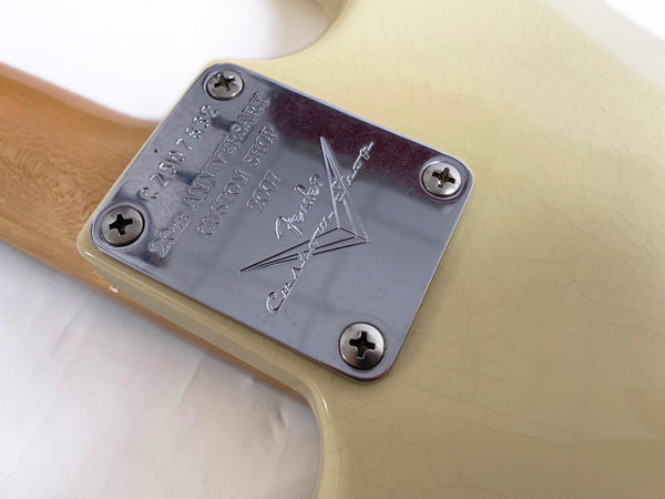 Close-up of Fender Custom Shop 20th Anniversary neck plate on cream electric guitar body with visible wood grain neck and vintage crackle finish
