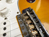 Close-up of vintage Fender electric guitar bridge and volume knob on sunburst body with white pickguard and single coil pickups