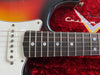 Close-up of sunburst electric guitar neck and white single-coil pickups resting in red velvet Fender Custom Shop guitar case interior