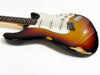Vintage sunburst electric guitar with wear and paint chips showing aged finish and white pickguard and control knobs on white background