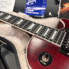 Close-up of cherry red Gibson electric guitar neck and body in plush case with rhythm and treble pickup selector switch and Gibson USA sticker in background