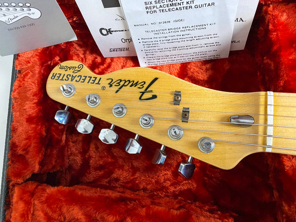 Fender Telecaster Custom guitar headstock with six tuning pegs inside orange plush lined guitar case with Telecaster bridge replacement kit instructions and warranty papers
