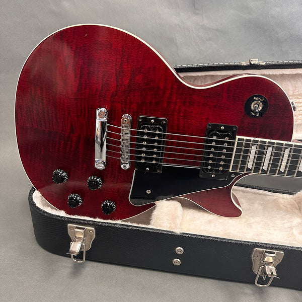 Red sunburst electric guitar body with chrome bridge and black pickups inside a black hard case with cream plush interior