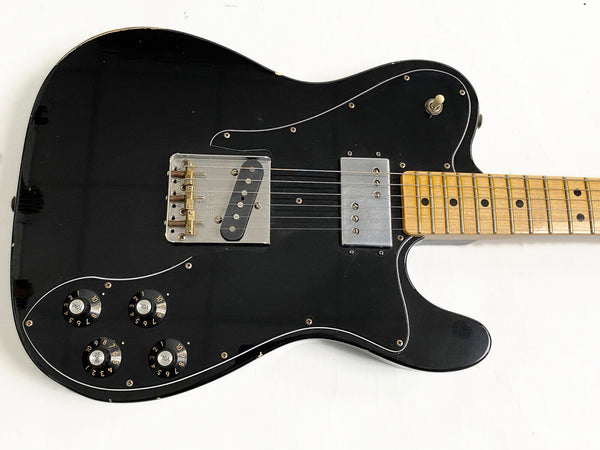 Black electric guitar with maple fretboard and four control knobs on white background, vintage guitar body style