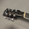 Close-up of Gibson Les Paul guitar headstock with tuning pegs and strings on gray background