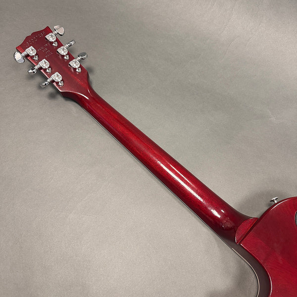 Back view of red electric guitar neck and headstock with chrome tuning pegs on gray background from Coffee House Guitars