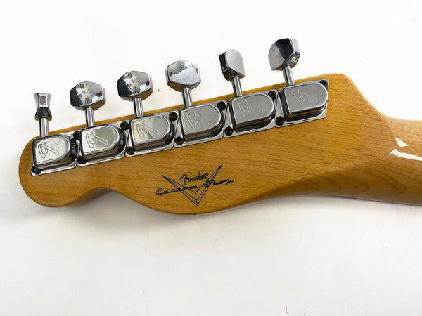 Close-up of Fender Custom Shop guitar headstock with six chrome tuning pegs on natural wood finish neck