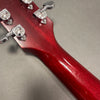 Close-up of red guitar neck back with chrome tuning pegs and clear wood grain texture on grey background