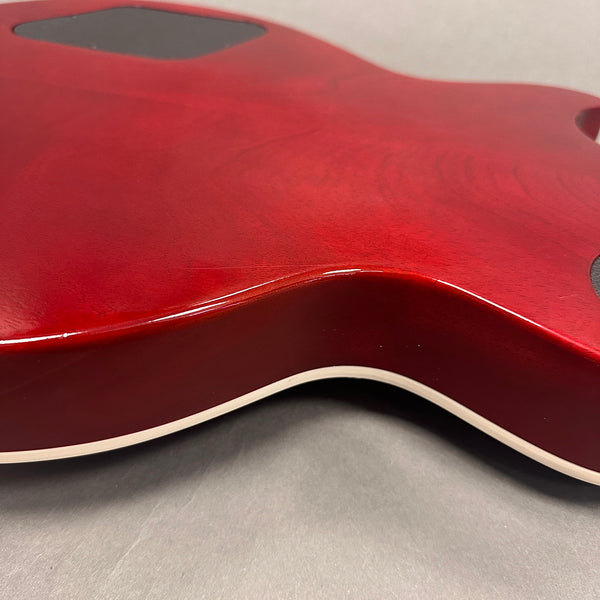 Close-up of red electric guitar body with white binding and visible wood grain finish