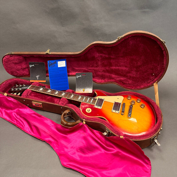 Gibson Les Paul electric guitar with sunburst finish in open brown hardshell case with red plush interior and Gibson warranty cards and accessories