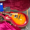 Gibson Les Paul electric guitar with sunburst finish in pink-lined hardshell case with Gibson tag and blue warranty card.