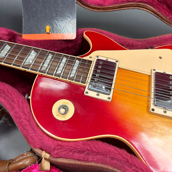 Close-up of vintage sunburst electric guitar with cream pickguard and humbucker pickups in a plush pink guitar case