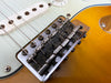 Close-up of vintage Fender guitar bridge with rusty saddles and strings on sunburst electric guitar body