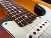Close-up of electric guitar frets, steel strings, and white single-coil pickups with sunburst finish body and white pickguard.
