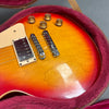 Close-up of sunburst electric guitar body with chrome bridge and amber control knobs in plush pink guitar case