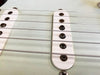 Close-up of vintage electric guitar single-coil pickups and strings on white guitar body