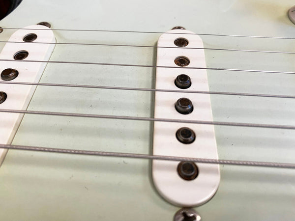 Close-up of vintage electric guitar single-coil pickups and strings on white guitar body