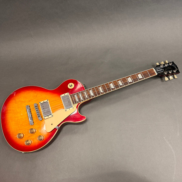 Sunburst Gibson Les Paul Standard electric guitar with humbucker pickups and cream pickguard on gray background