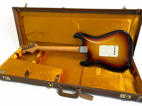 Vintage sunburst electric guitar body and neck laying inside open brown hard guitar case with yellow velvet interior, showing back side and vintage wear marks