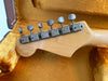 Vintage guitar headstock with six old metal tuning pegs inside a worn orange plush guitar case