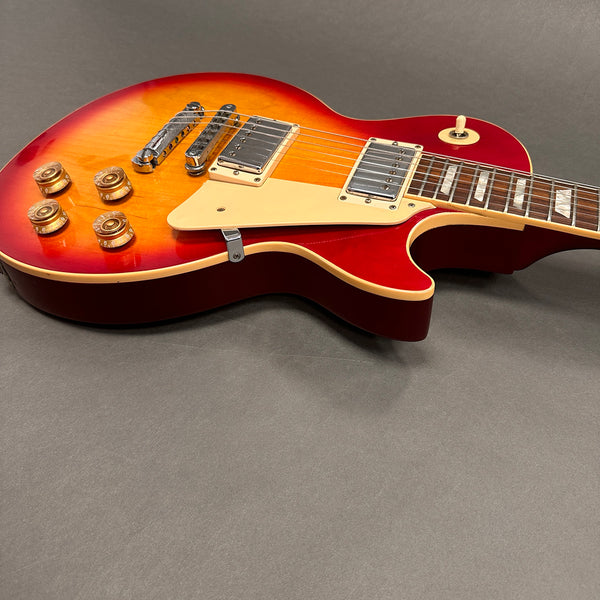 Sunburst electric guitar with dual humbucker pickups, cream pickguard, and four control knobs on gray background