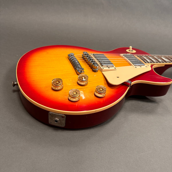 Electric guitar with sunburst finish, chrome pickups, cream pickguard, and amber control knobs, displayed on grey background