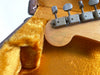 Close-up of vintage guitar tuning pegs and signed wooden headstock inside plush yellow guitar case lining