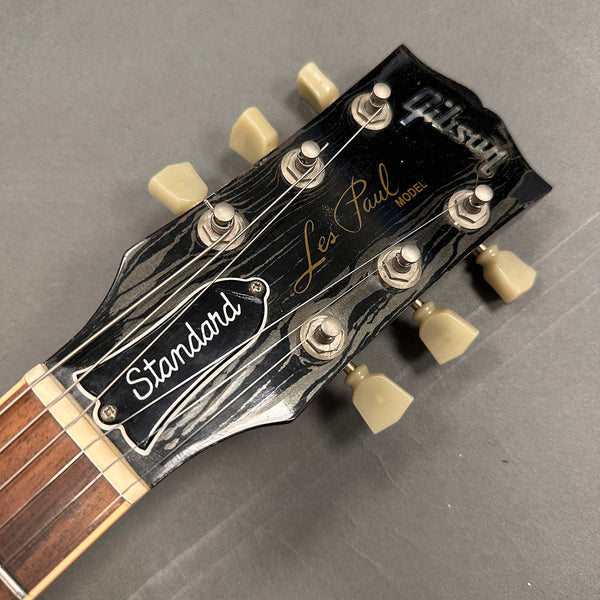 Close-up of Gibson Les Paul Standard guitar headstock with tuning pegs and strings on gray background