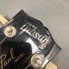 Close-up of worn black Gibson Les Paul guitar headstock showing vintage tuners and faded logo lettering