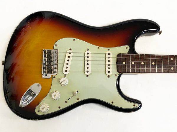 Vintage sunburst electric guitar with three single-coil pickups and rosewood fretboard, close-up of body and controls on white background