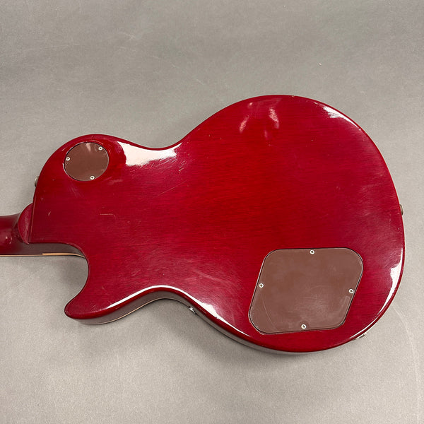Back of red electric guitar body showing control cavity covers and glossy finish on gray background