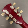 Close-up of vintage red guitar headstock showing six white tuning pegs and metal tuning machines on gray background