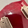 Close-up of serial number on red electric guitar body near silver Deluxe hardware screws, showing scratches and wear
