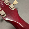 Close-up of vintage red guitar headstock back with vintage tuning machines and cream tuning pegs, showing wear and patina
