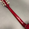 Close-up of a red finished guitar neck and tuning pegs on a gray background