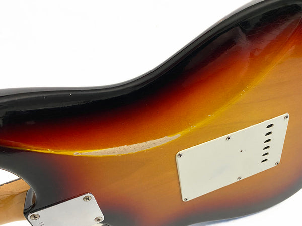 Close-up of sunburst electric guitar body showing wear and scratches near back plate and neck joint