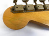 Close-up of vintage guitar headstock showing aged metal tuning machines and faded autograph on maple wood finish