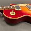 Close-up of red and sunburst electric guitar body with cream binding, pickup switch, and humbucker pickups on gray background