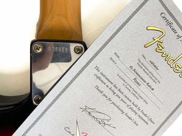 Fender certificate of authenticity for 62 Stratocaster Relic guitar with serial number R35953 next to guitar neck plate with serial number R35958