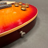 Close-up of electric guitar body with sunburst finish, amber control knobs, and chrome bridge on gray background