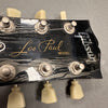 Close-up of Gibson Les Paul guitar headstock with tuning pegs and logo on black finish