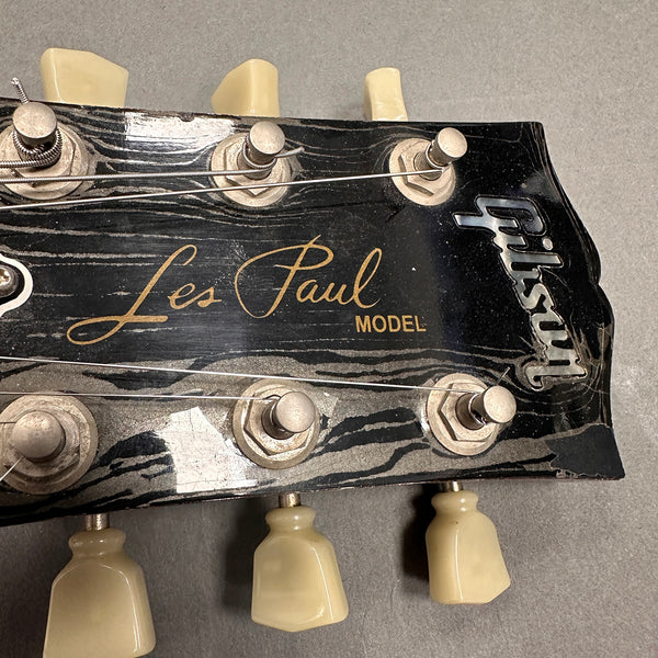 Close-up of Gibson Les Paul guitar headstock with tuning pegs and logo on black finish