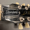 Close-up of Gibson Les Paul Standard guitar headstock with vintage tuning pegs and strings on gray background