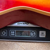 Close-up of red guitar body on a DYMO digital scale displaying weight of 9 pounds 14.3 ounces