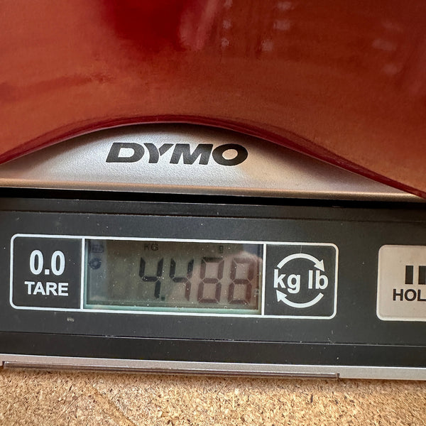 Digital DYMO scale showing guitar weight at 4.488 pounds with part of a reddish-brown guitar body visible on top