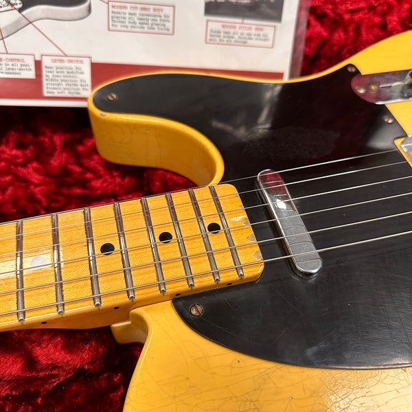 Close-up of vintage electric guitar neck and black pickguard with single-coil pickup on red plush background