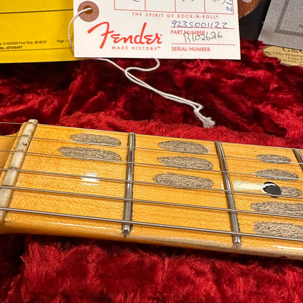 Close-up of vintage Fender guitar maple fretboard with worn dot inlays and strings on red plush case lining, accompanied by Fender hang tag and paperwork