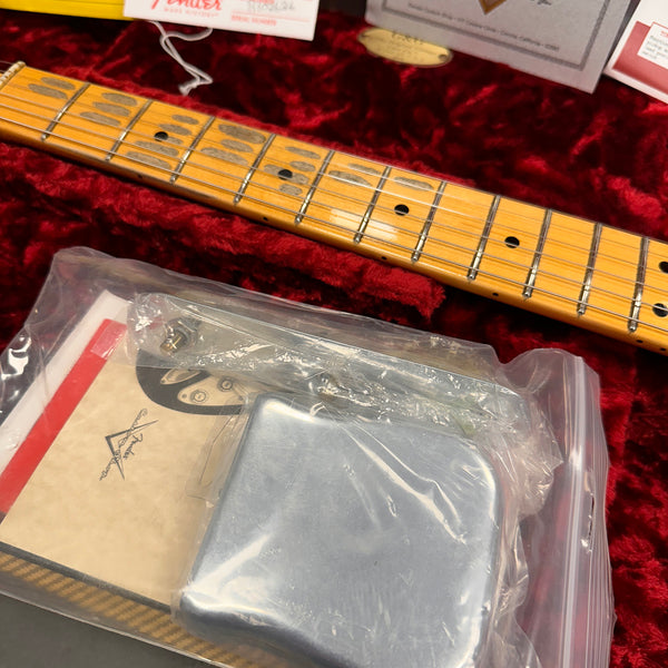 Close-up of Fender guitar maple fretboard with vintage pickup and paperwork inside a red velvet guitar case