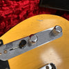 Close-up of vintage yellow electric guitar control plate with chrome volume and tone knobs and black switch on red plush background